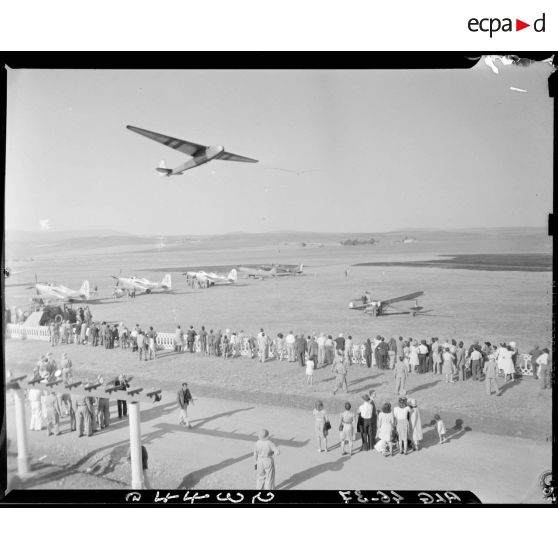 Plan d'ensemble d'un meeting aérien à Constantine : vue d'un planeur en plein vol.