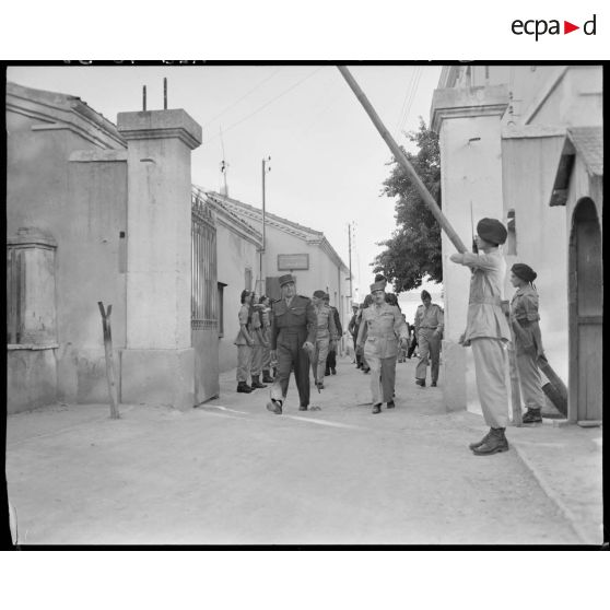 Le général Jean de Lattre de Tassigny quitte une caserne, accompagné du général de corps d'armée Henry Martin et de personnalités militaires.