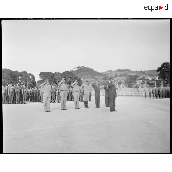 Le général Jean de Lattre de Tassigny salue des autorités militaires, accompagné du général de corps d'armée Henry Martin, du général de brigade Jean Breuillac et d'autorité militaires.