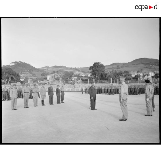 Le général Jean de Lattre de Tassigny s'adresse à une autorité militaire, sous le regard du général de corps d'armée Henry Martin, du général de Brigade Jean Breuillac, de personnalités et  troupes militaires.