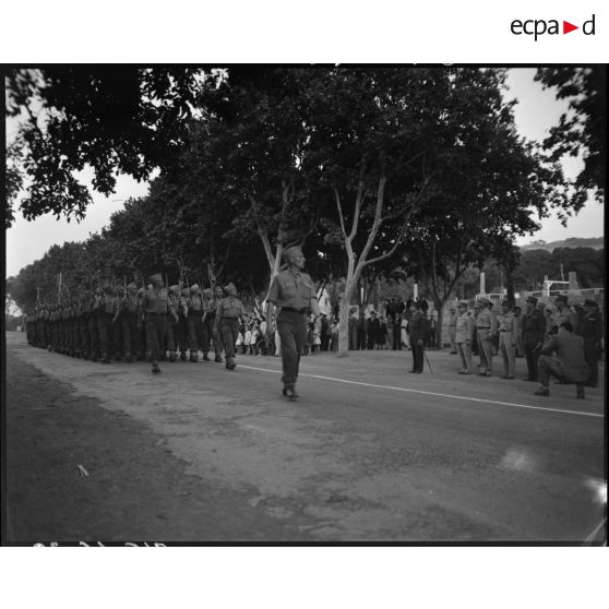 Une unité militaire défile sous le regard du général Jean de Lattre de Tassigny.