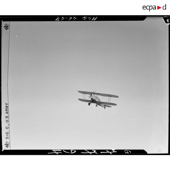 Vue en contre-plongée d'un biplan d'entrainement de voltige aérienne.