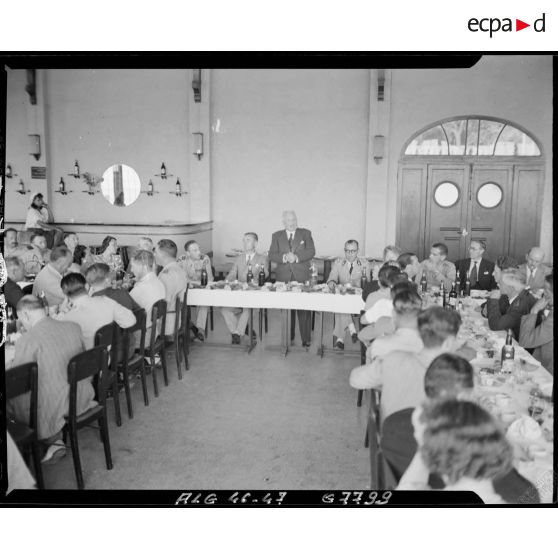 Une personnalité civile prononce un discours lors d'un repas, en présende de personnalités militaires et civiles.