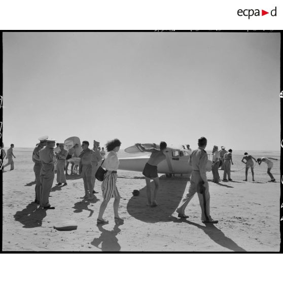 Des officiers-élèves préparent au vol un planeur, sous le regard d'autorités civiles et militaires.