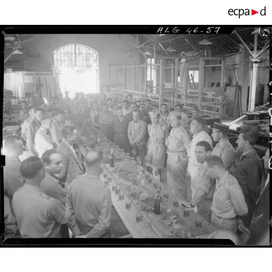 Vue en plongée d'une réception à l'intérieur de l'établissement général du matériel (EGM), en présence d'autorités militaire, civiles et d'ouvriers.