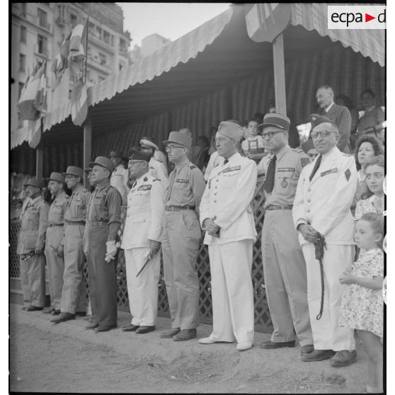 Plan d'ensemble de la tribune depuis laquelle des autorités civiles et militaires asistent à la cérémonie à l'occasion du retour à Alger du 9e bataillon de zouaves (BZ), sur la place du forum d'Alger.