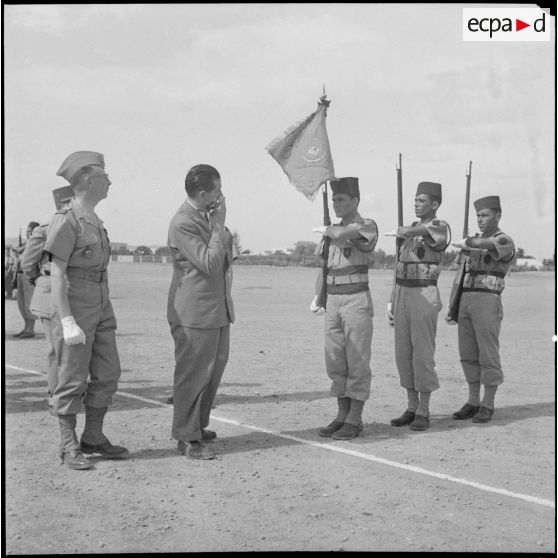 Le ministre des Armées Edmond Michelet passe en revue la garde au drapeau d'une unité militaire.