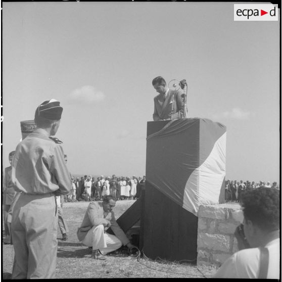 Le ministre des Armées, Edmond Michelet, s'apprête à prononcer un discours, sous le regard d'autorités civiles et militaires, juché sur une estrade.