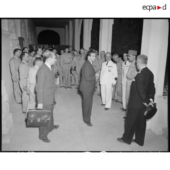 Le général de corps d'armée Henry Martin s'entretient avec le ministre des armées, Edmond Michelet et le gouverneur général de l'Algérie, Yves Chataigneau ; sous le regard d'autorités civiles et militaires.