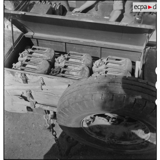 Plan en plongée d'un coffre rempli de jerricanes.