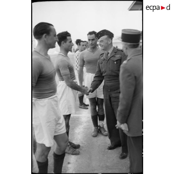Général de brigade félicitant une équipe de football militaire lors de la finale au stade municipal d'Alger.