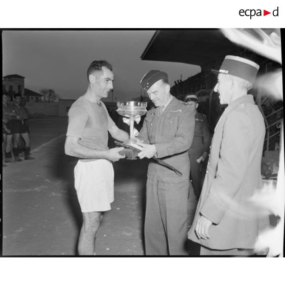 Remise de la coupe à un joueur lors d'une finale de football et basket-ball militaire au stade municipal d'Alger.
