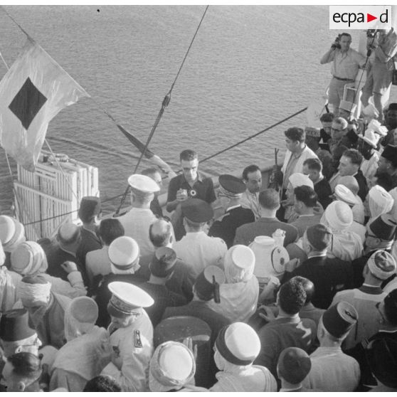 Plan en plongée du départ des pèlerins musulmans pour la Mecque à bord de l'Atlas : une autorité militaire s'entretient avec une personnalité civile.