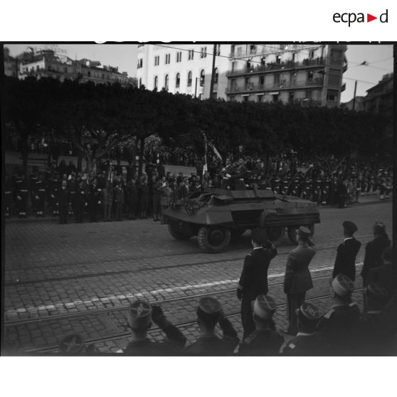 Défilé d'un véhicule blindé, sous le regard d'autorités civiles et militaires.