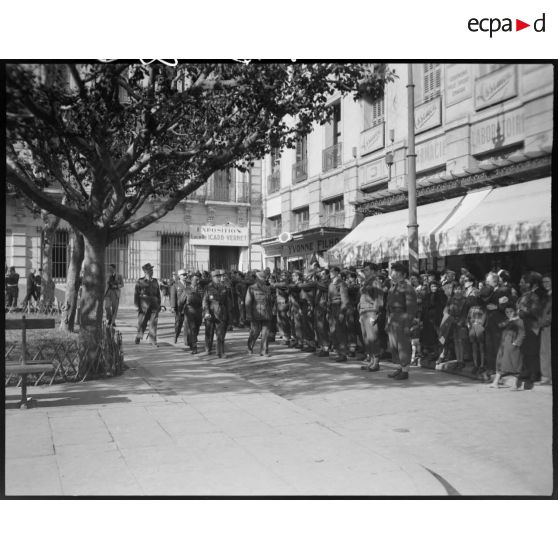 Le général de corps d'armée Henry Martin passe en revue une unité militaire, accompagné d'autorités militaires, dans les rues d'Alger, à l'occasion de la cérémonie organisée pour son départ.
