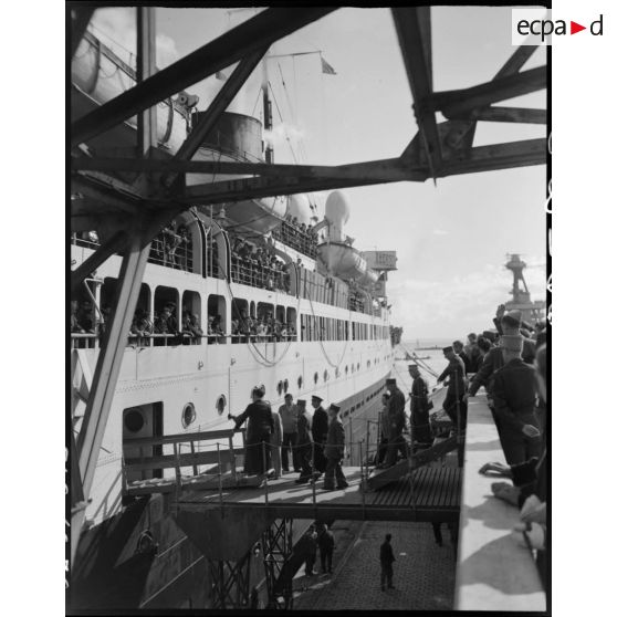 Des personnalités militaires montent à bord d'un bateau, à quai, dans le port d'Alger : le général de corps d'armée Henry Martin quitte Alger.