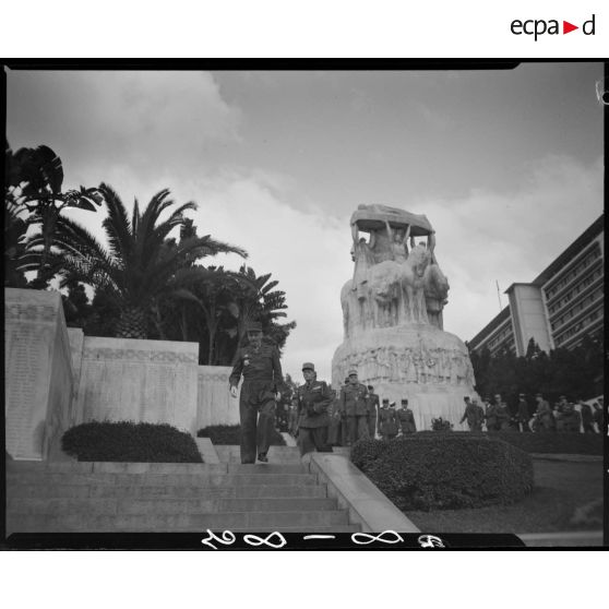 Plan en contre-plongée du général Duché qui quitte le monument aux morts d'Alger, suivi par des autorités militaires.