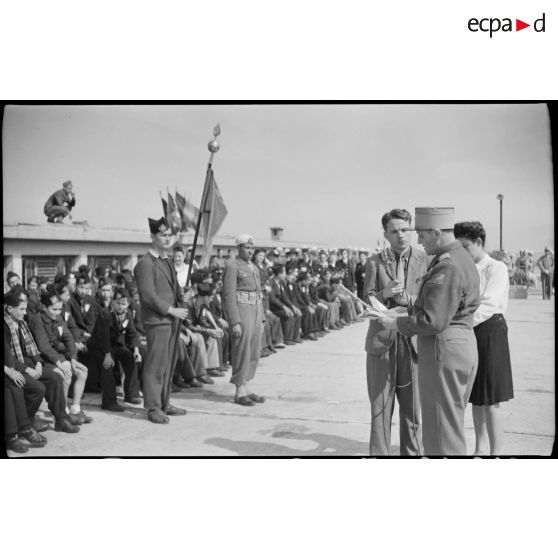 Un journaliste enregistre le discours prononcé par une personnalité militaire pour l'arrivée de jeunes gens originaires de Saint-Etienne, sur le port d'Alger.