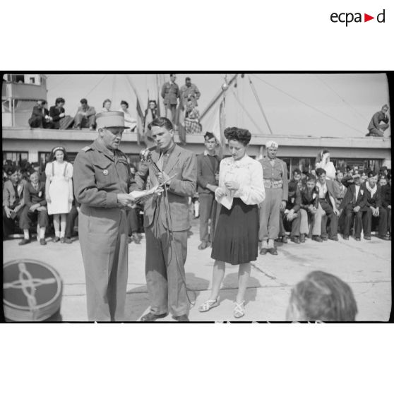 Un journaliste enregistre le discours prononcé par une personnalité militaire pour l'arrivée de jeunes gens originaires de Saint-Etienne, sur le port d'Alger.