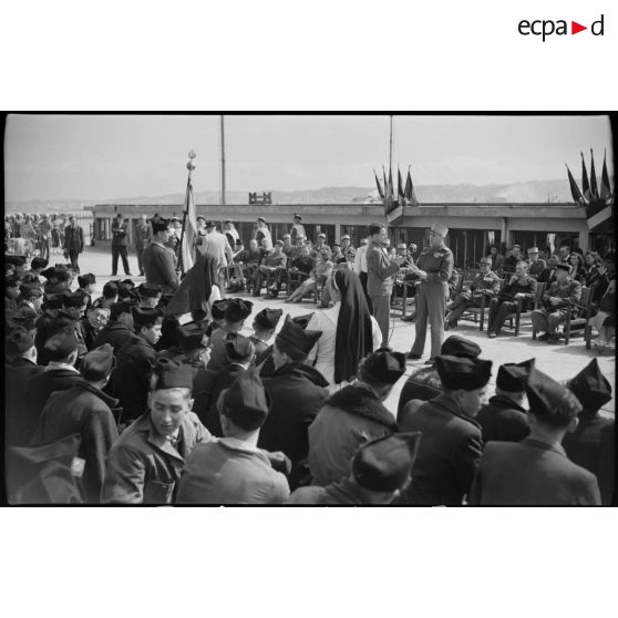 Une personnalité militaire prononce un discours, sous le regard d'un journaliste, d'autorités militaires et civiles et des jeunes gens originaires de Saint-Etienne arrivés au port d'Alger.