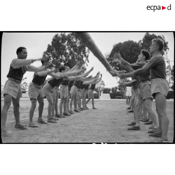 Des aides moniteurs d'éducation physique militaire (EPM) effectuent un exercice d'entrainement avec un tronc d'arbre.