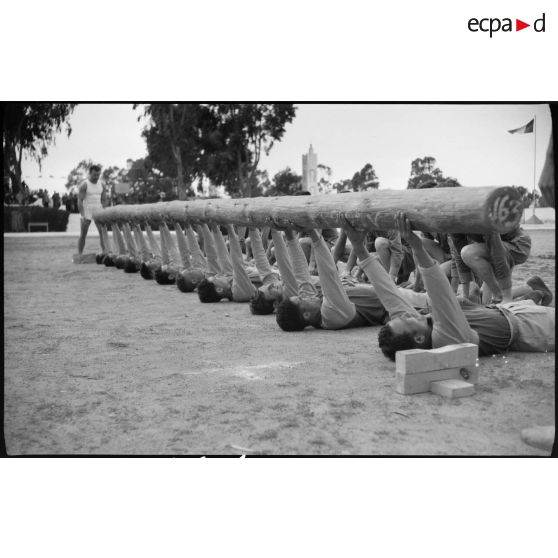 Des aides moniteurs d'éducation physique militaire (EPM) effectuent un exercice d'entrainement avec un tronc d'arbre.