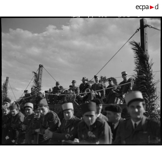 Plan en contre-plongée de la tribune depuis laquelle des autorités militaires assistent à la finale des championnats militaires de rugby.