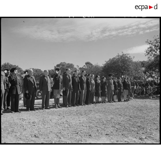 Photographie de groupe rassemblant des autorités civiles et militaires, parmi lesquelles le général Schlesser, qui salue au drapeau.