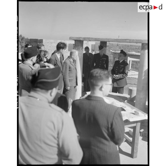 Une autorité militaire prononce un discours, assistée du général Schlesser, sous le regard de personnalités civiles et militaires.