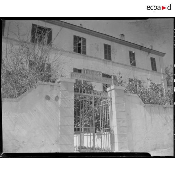 Plan en contre-plongée de l'entrée principale du centre de rééducation de convalescents, à l'extérieur de l'enceinte, à Alger.