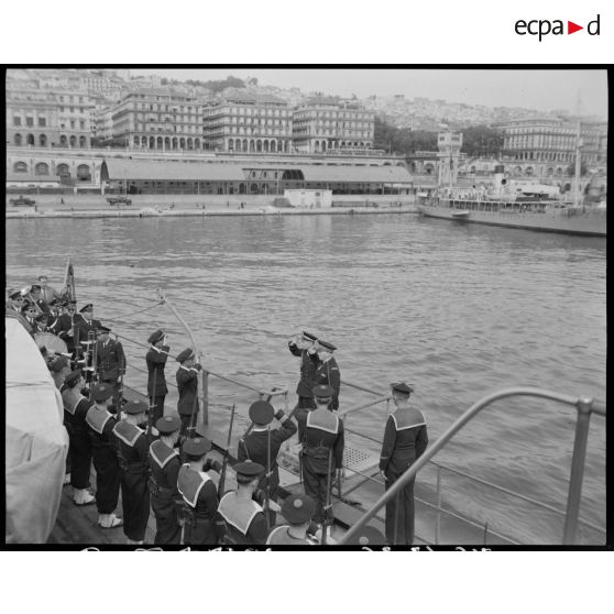 Plan en contre-plongée de l'arrivée à bord de l'officier Jean-Marie Querville, sur le croiseur Suffren, à quai dans le port d'Alger.