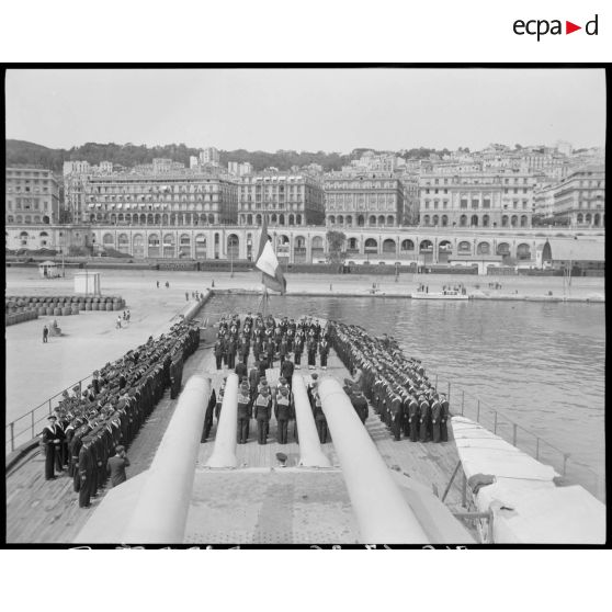 Cérémonie militaire donnée à l'occasion de la remise de la croix de guerre à la compagnie de débarquement du croiseur Suffren, à quai, dans le port d'Alger.