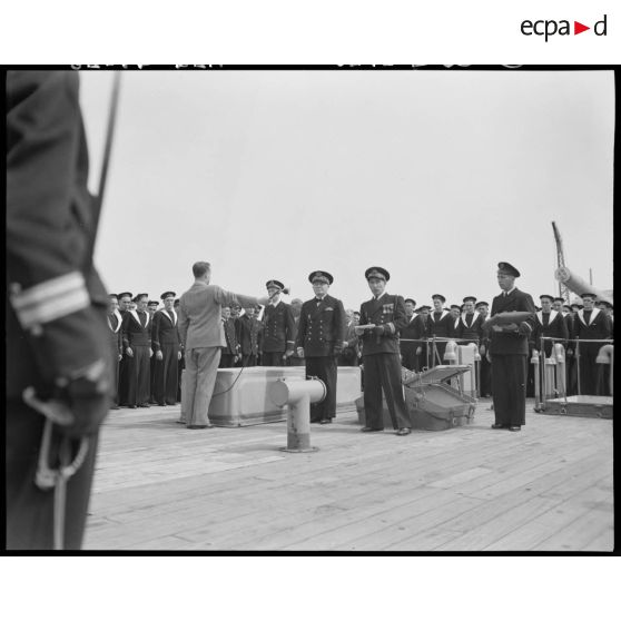 Une autorité militaire prononce un discours à l'occasion de la remise de la croix de guerre à la compagnie de débarquement du croiseur Suffren, à quai, dans le port d'Alger.