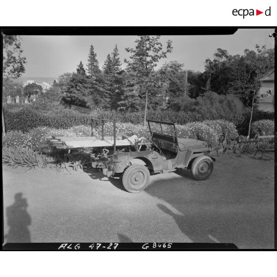 Plan d'ensemble d'une voiture Jeep transformée en transport sanitaire, à l'arrière de laquelle deux brancards ont été fixés.