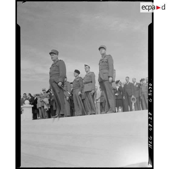 Plan en contre-plongée du général Duché, accompagné d'autorités civiles et militaires.