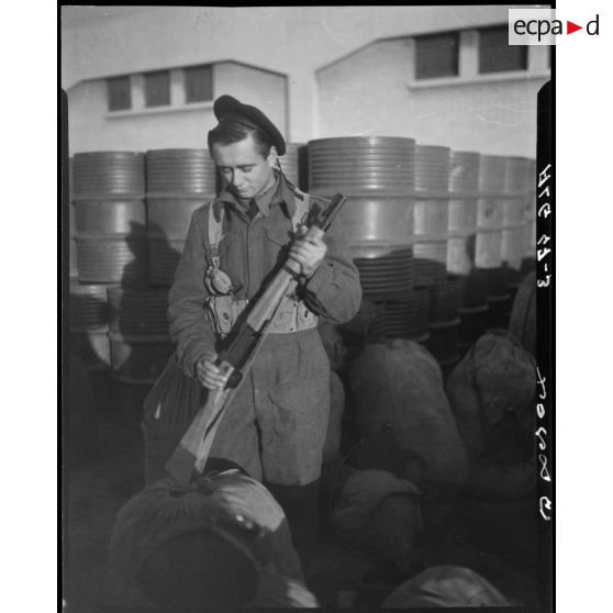 Portrait d'un soldat armé à bord du paquebot  Athos II, à quai, dans le port d'Alger.