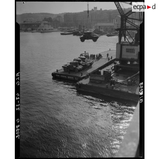 Plan d'ensemble du débarquement d'un véhicule militaire à l'aide d'une grue portuaire.