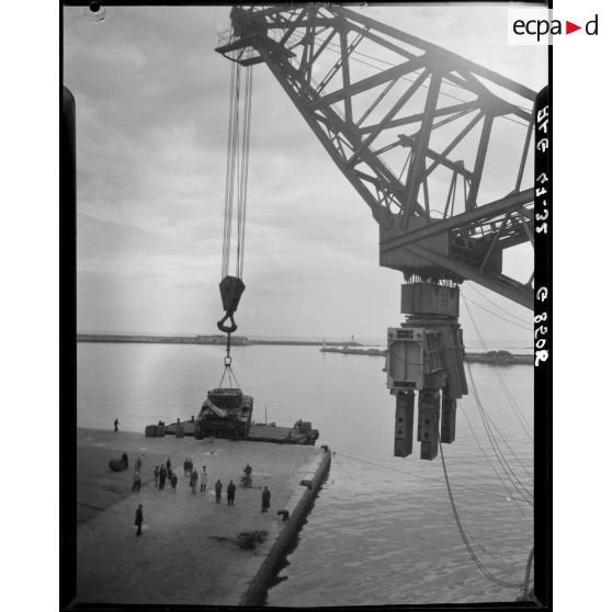Débarquement d'un véhicule militaire à l'aide d'une grue portuaire.