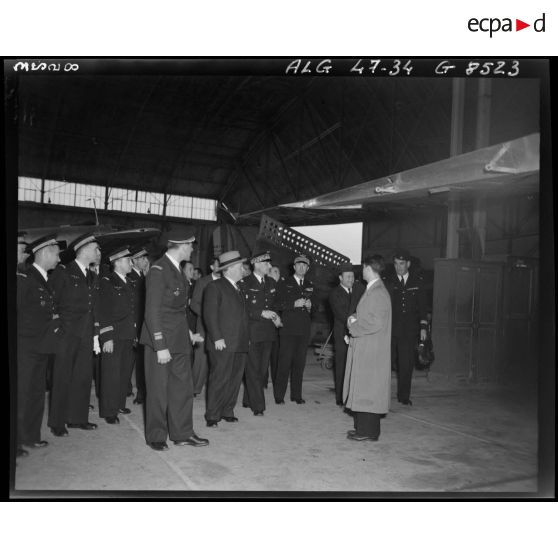 Le ministre de l'Air André Maroselli s'entretient avec des autorités civiles et militaires, dans un hangar.