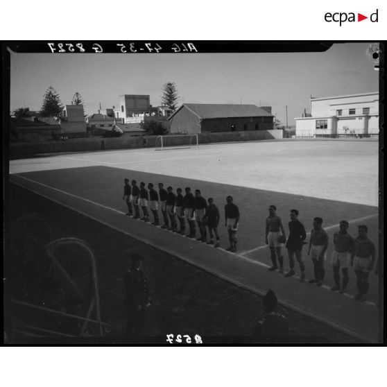 Plan en plongée de deux équipes de football qui vont s'affronter lors du match national France-Afrique française du nord (AFN).