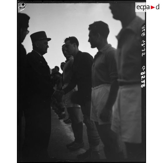 Le général Duché salue un joueur d'une équipe de football.