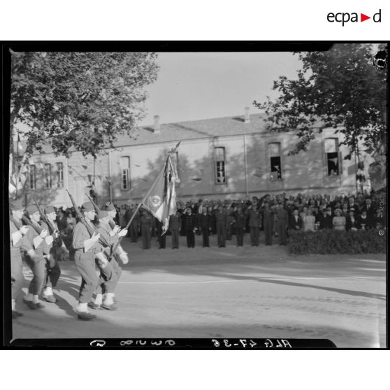 Garde au drapeau d'une unité militaire, sous le regard d'autorités civiles et militaires.