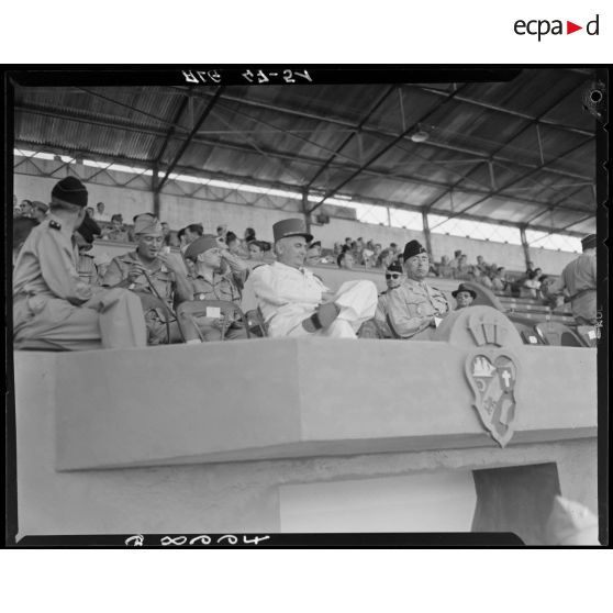 Plan en contre-plongée de la tribune depuis laquelle le général Duché assiste aux championnats sportifs militaires.