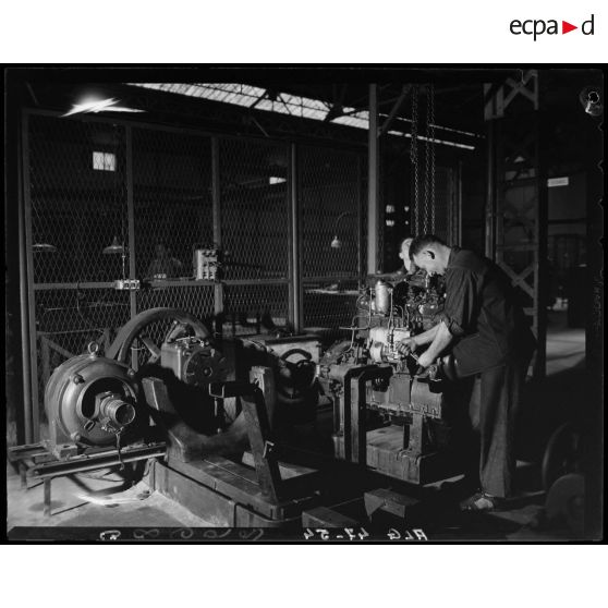 Des ouvriers de montage en construction automobile assemblent des pièces et composants d'un moteur, dans un atelier des usines Berliet, à Alger.