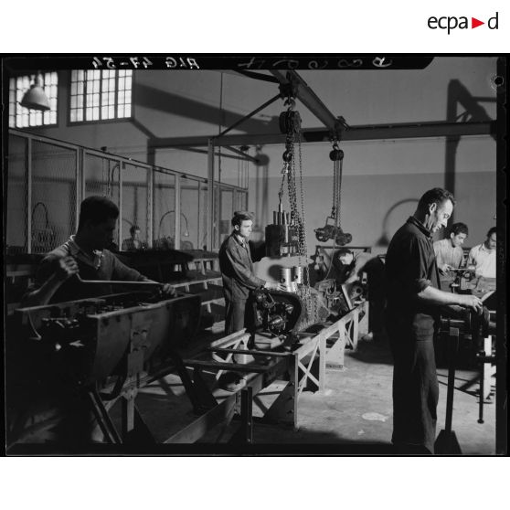 Des ouvriers de montage en construction automobile assemblent des pièces et composants, dans un atelier des usines Berliet, à Alger.