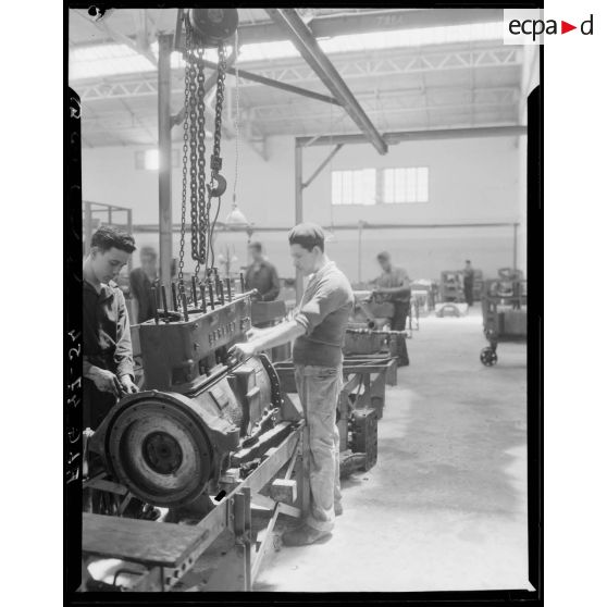 Des ouvriers de montage en construction automobile assemblent des pièces et composants, dans un atelier des usines Berliet, à Alger.