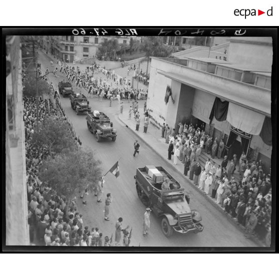 Rapatriement des premiers corps tombés au champ d'honneur, à bord de véhicules militaires : défilé sous le regard d'autorités civiles, militaires et de la population civile, dans les rues d'Alger.