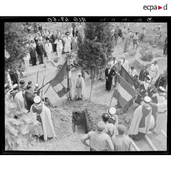 Des autorités civiles, militaires et des personnalités civiles se recueillent devant un cercueil, après son inhumation, dans un cimetère, à Alger.