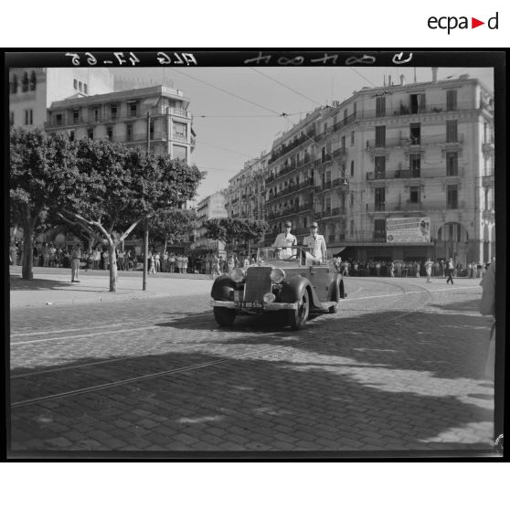 Le général Olleris défile à bord d'une voiture, accompagné d'une autorité militaire, dans les rues d'Alger.