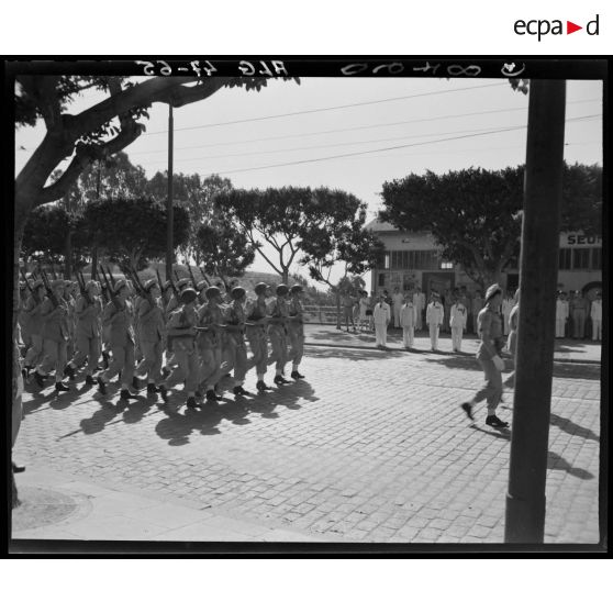 Défilé d'une unité militaire, sous le regard d'autorités militaires.